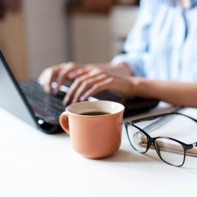 Remote working from home. Freelancer workplace in kitchen with laptop, cup of coffee